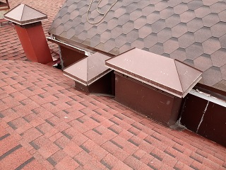 Дымоходные трубы и вентшахты установлены на полукруглых крышах гаражного кооператива.
